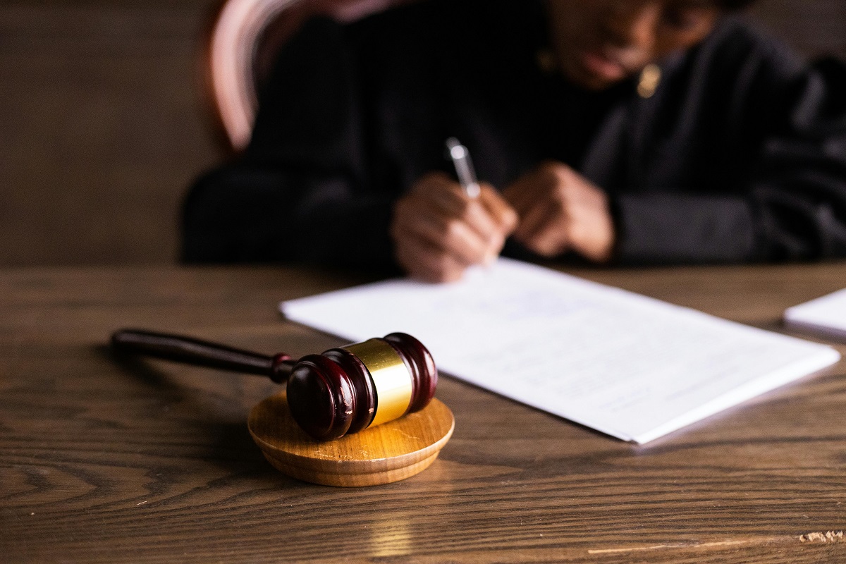 judge writing on legal paperwork with a gavel nearby